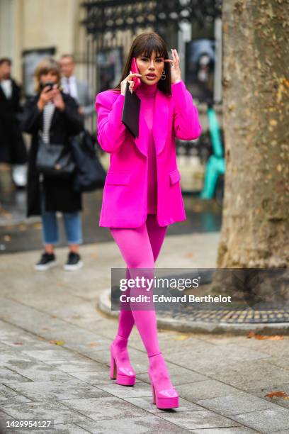 Guest wears diamonds logo pendant earrings from Valentino, a neon pink turtleneck ribbed wool pullover from Valentino, a neon pink blazer jacket from...