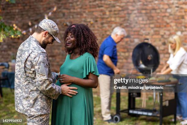 soldier reuniting with his pregnant wife after coming home from military service - homecoming stock pictures, royalty-free photos & images