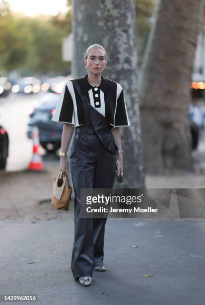 Fashion week guest seen wearing an oversize black and white shirt and leather dungarees, outside Akris during Paris Fashion Week on October 01, 2022...