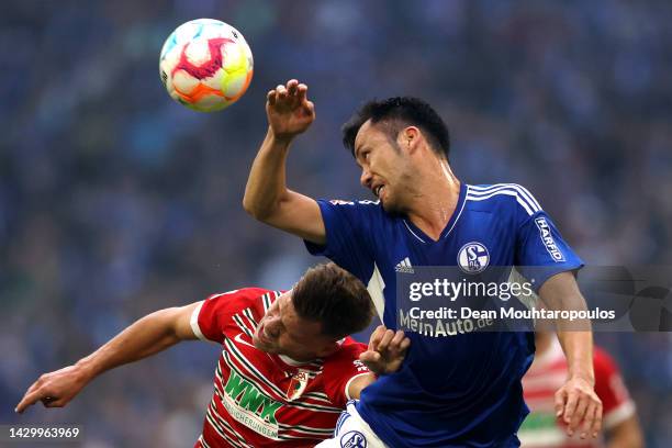 Maya Yoshida of FC Schalke 04 challenges for the high ball with Florian Niederlechner of Augsburg during the Bundesliga match between FC Schalke 04...