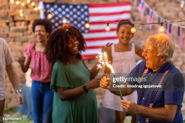multi-generationfamily having fun with sparklers while celebrating american holiday - happy smiling people multi generations stock pictures, royalty-free photos & images