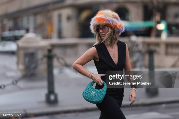 Karin Teigl wearing a colorful hat, a black Zara veste, a long black Zara skirt, Cartier yellow gold diamond Love Bracelet and Bulgari Bzero diamond...