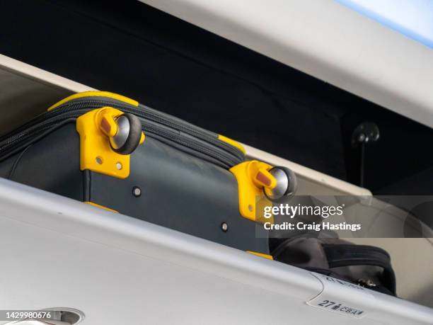 pre flight departure boarding - over sized cabin baggage and luggage being stuffed into over head storage compartments that won't close properly. commuters pack to much luggage when travelling and avoid checked baggage costs at their own risk. - hand luggage stock pictures, royalty-free photos & images