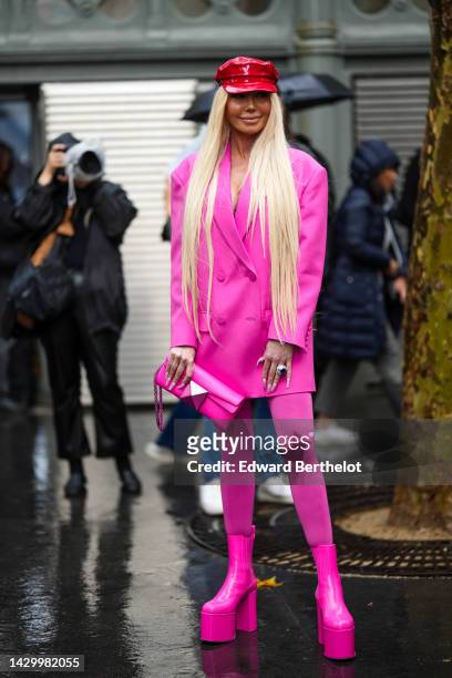 Guest wears a red shiny varnished leather / vinyl cap, a neon pink blazer jacket from Valentino, a neon pink shiny leather clutch from Valentino,...