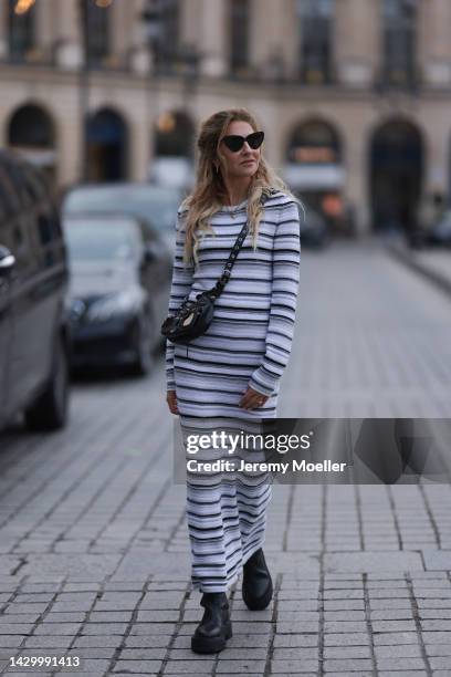 Sue Giers wearing SoSue striped knit dress, black Celine boots, Balenciaga le Cagole black bag, black Balenciaga shades during Paris Fashion Week on...