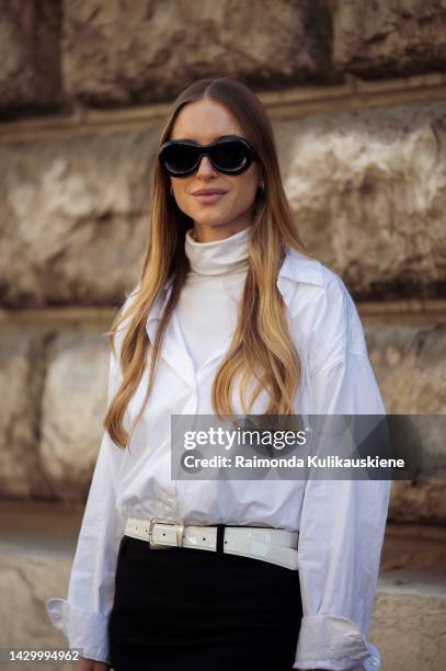 Pernille Teisbaek wearing a black long skirt, white boots, white leather belt, white turtle neck top, white shirt, black sunglasses from Loewe, and...