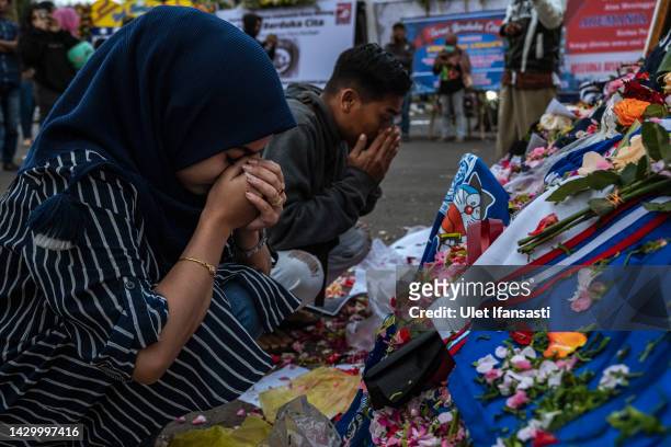 Woman prays as they pay condolence to the victims outside Kanjuruhan Stadium on October 03, 2022 in Malang, Indonesia. A riot and stampede broke out...