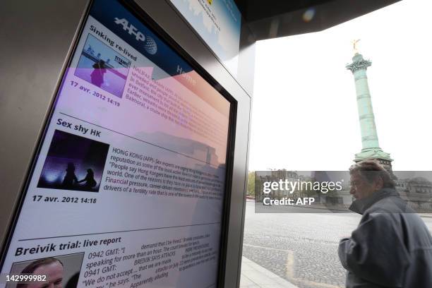 Person looks at a screen of the "Concept Abribus" bus shelter on the Bastille Square on April 17, 2012 in Paris, by France's JC Decaux, the biggest...