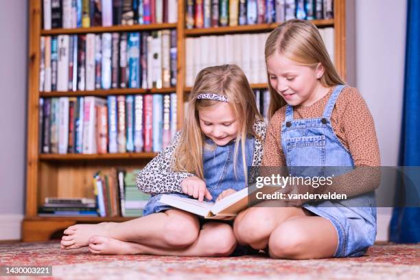 sorelle che leggono a casa - solo bambini foto e immagini stock
