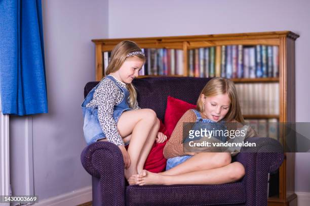 sisters reading at home - curled up reading book stock pictures, royalty-free photos & images