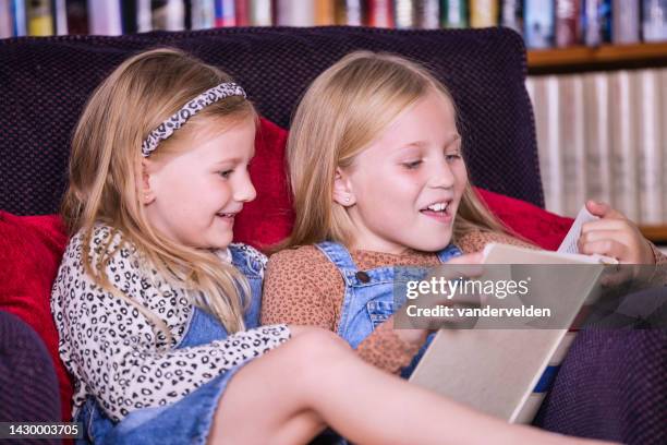 sisters reading at home - curled up reading book stock pictures, royalty-free photos & images