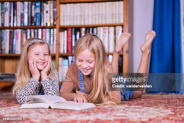 sisters reading at home - barefoot girl stock pictures, royalty-free photos & images