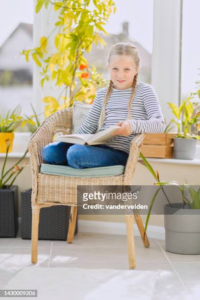 eight-year-old girl reading in the conservatory - curled up reading stock pictures, royalty-free photos & images