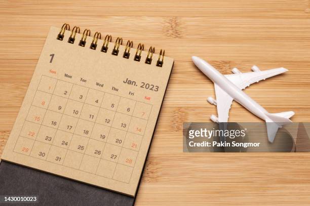 calendar desk 2023: january is the month for the organizer to plan and deadline with an airplane model against a wooden background. travel concept. - day of the week stockfoto's en -beelden