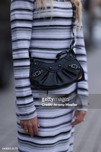 Sue Giers wearing SoSue striped knit dress, black Celine boots, Balenciaga le Cagole black bag, black Balenciaga shades during Paris Fashion Week on...