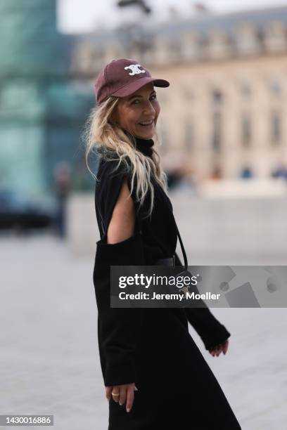 Sue Giers wearing black SoSue knit long dress, YSL black gold leather belt, black Celine mini bag and red Celine cap during Paris Fashion on October...