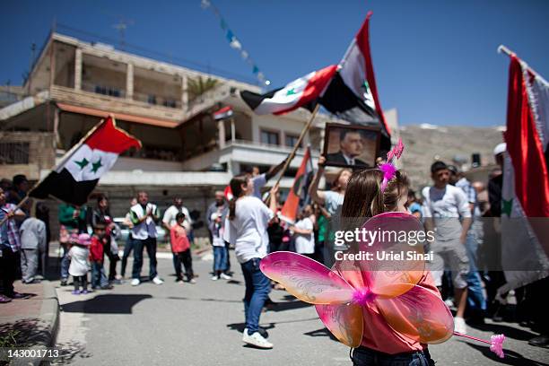 Druze residents of the the Israeli-occupied Golan Heights hold Syrian flags and portraits of Syria's President Bashar al-Assad, during a rally on...