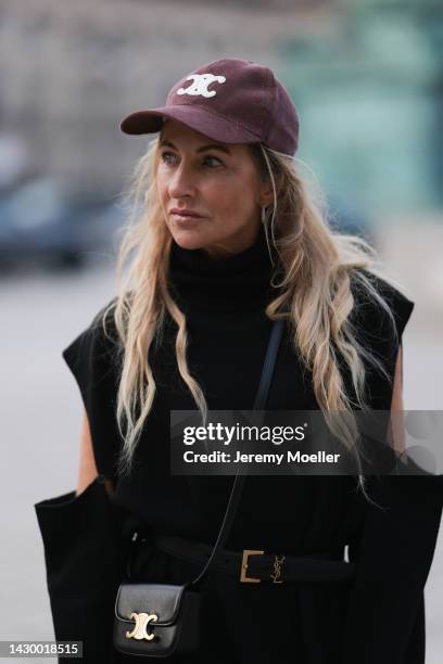 Sue Giers wearing black SoSue knit long dress, YSL black gold leather belt, black Celine mini bag and red Celine cap during Paris Fashion on October...