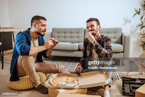 gay couple eating pizza - gay couple new house stock pictures, royalty-free photos & images