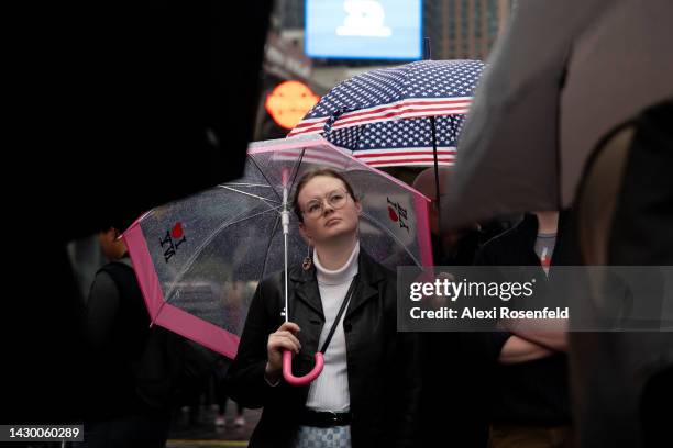 Woman stands under an I love NY umbrella in the rain to watch the "Curtain Up!" Festival in Times Square on October 2, 2022 in New York City. The...
