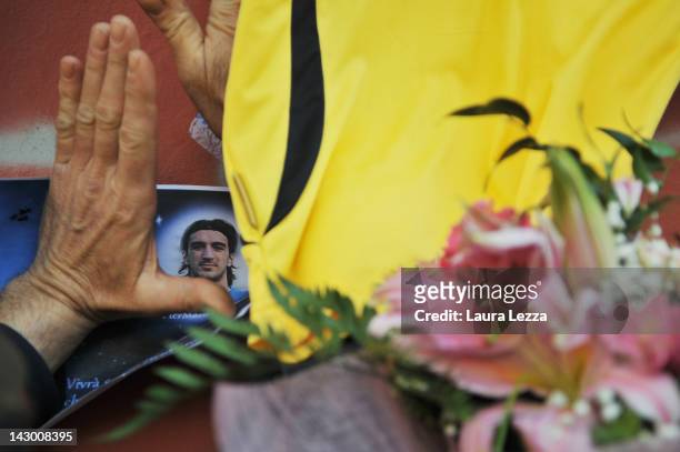 Fan views a photograph of Piermario Morosini amonst floral tributes outside Armando Picchi Stadium, where the coffin of the late AS Livorno...