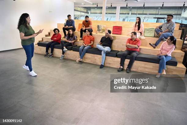 diverse group of people listening to mature adult speech  sitting together in a nonconventional classroom - employee engagement committee stock pictures, royalty-free photos & images