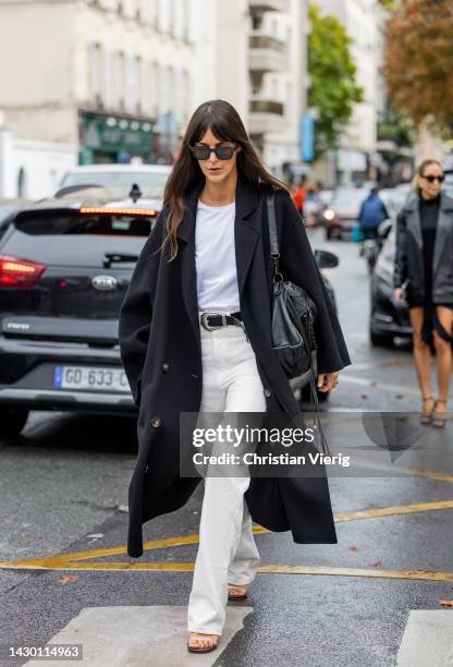 Leia Sfez wears black coat, Balenciaga bag, white pants outside Givenchy during Paris Fashion Week - Womenswear Spring/Summer 2023 : Day Seven on...