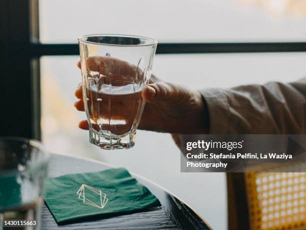 close up on hand holding a glass of water in restaurant - glass of water hand ストックフォトと画像