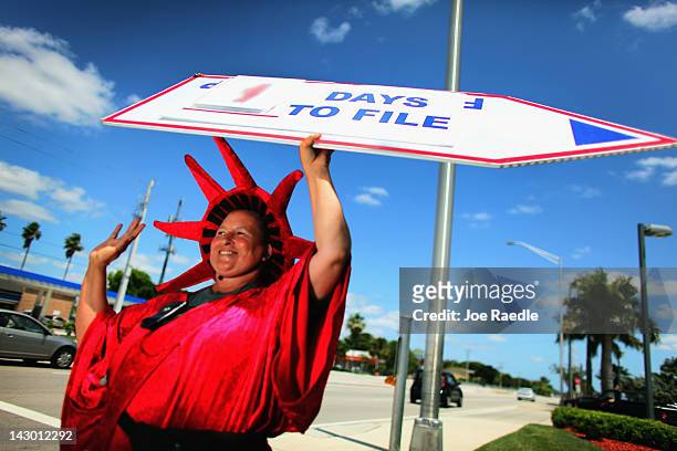 Cynthia Quiroz holds a sign reading, " 1 Days To File", as she directs people to the Liberty Tax Service office on April 17, 2012 in Miami, Florida....