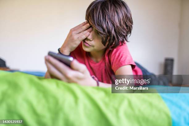 boy rubs eyes, sore eyes from smartphone screen - angry eyes stock pictures, royalty-free photos & images