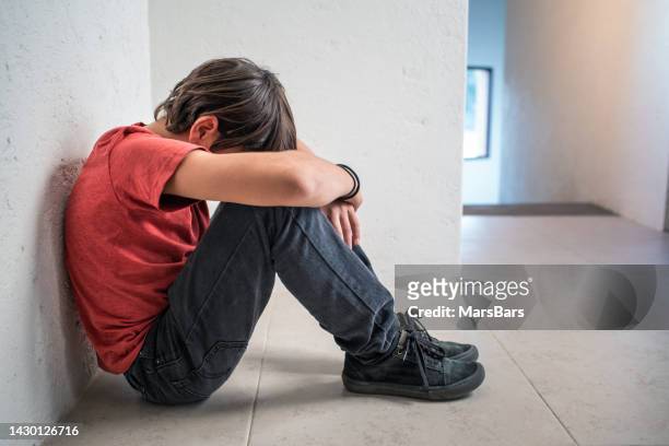 depressiver, trauriger, einsamer junge, der auf dem boden sitzt - vulnerable children stock-fotos und bilder