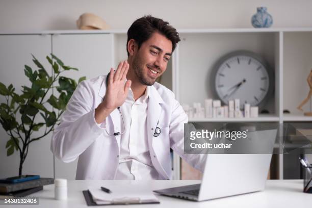 the doctor, who finished his online interview, waved goodbye to his patient - doctor laptop stock pictures, royalty-free photos & images