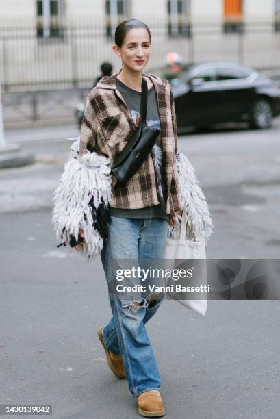 Model Rachel Marx poses wearing a square flannel shirt denim trousers, Ugg boots and a Jil Sander black cannolo bag after the Sacai show during Paris...