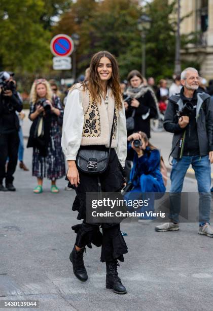 Model Taylor Hill wears white blouse, beige vest, black ruffled bag, ruffled pants outside Zimmermann during Paris Fashion Week - Womenswear...