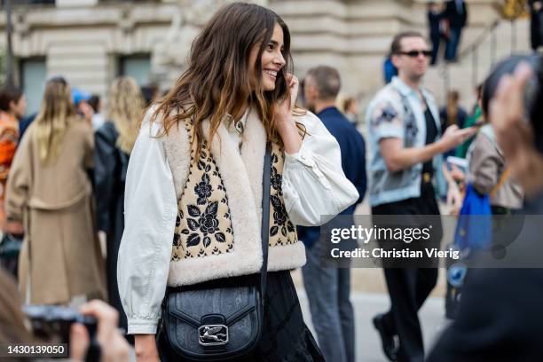 Model Taylor Hill wears white blouse, beige vest, black ruffled bag, ruffled pants outside Zimmermann during Paris Fashion Week - Womenswear...