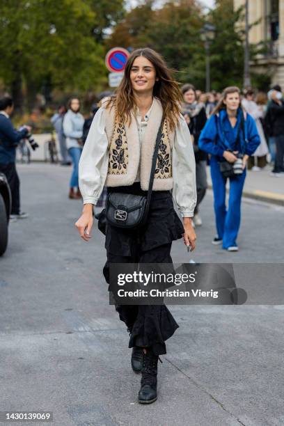 Model Taylor Hill wears white blouse, beige vest, black ruffled bag, ruffled pants outside Zimmermann during Paris Fashion Week - Womenswear...