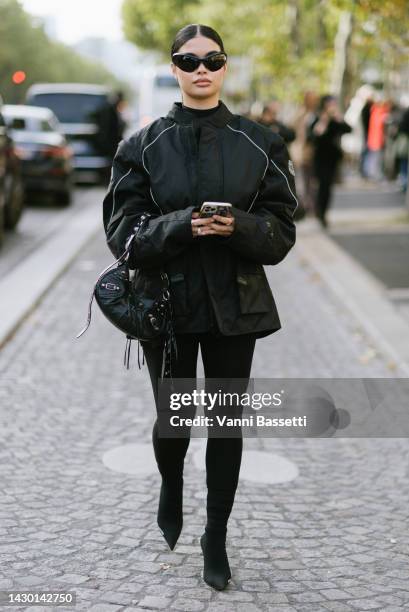 Guest poses wearing Balenciaga sunglasses and a Balenciaga black studded leather bag after the Yeezy Season 9 showduring Paris Fashion Week -...