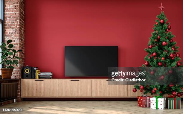 a nostalgic retro living room with with a tv on a cabinet in front of a red plaster wall and partly ruined brick wall and christmas decoration - lcd television stockfoto's en -beelden