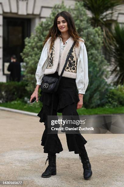 Taylor Hill is seen wearing a white shirt, cream floral vest, black ruffled pants and black bag outside the Zimmermann show during Paris Fashion Week...