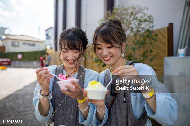 若い女性のまつりパフォーマーが一休みして路上でかき氷「かきごり」を食べている - かき氷 ストックフォトと画像