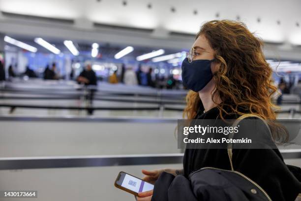 traveller in face mask at the airport waiting in the line with flight ticket on the phone. - john f kennedy airport stock pictures, royalty-free photos & images