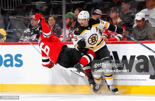 Connor Clifton of the Boston Bruins checks John Marino of the New Jersey Devils during the second period at the Prudential Center on October 03, 2022...