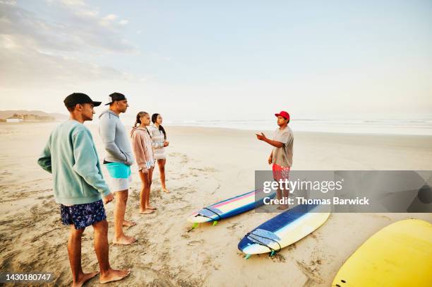 wide shot of family on tropical beach taking surf lesson - advice woman travel traveling stock pictures, royalty-free photos & images