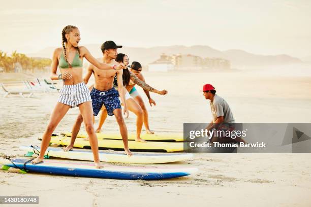 wide shot of family on tropical beach taking surf lesson - route 13 stock pictures, royalty-free photos & images