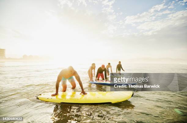 Wide shot of family entering ocean with surfboards during surf lesson
