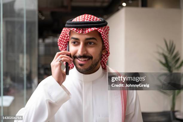 candid close-up of saudi businessman using smart phone - international day one stock pictures, royalty-free photos & images