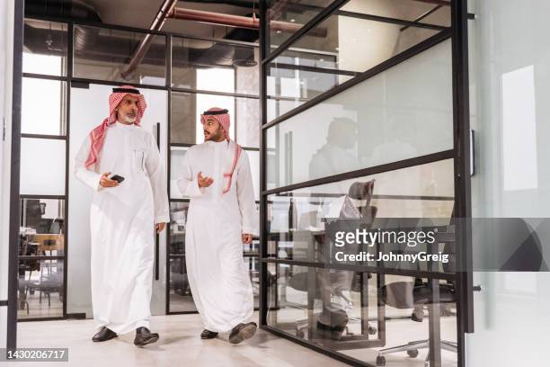 riad-profis zu fuß zu einem meeting in einem modernen büro - saudi guy stock-fotos und bilder