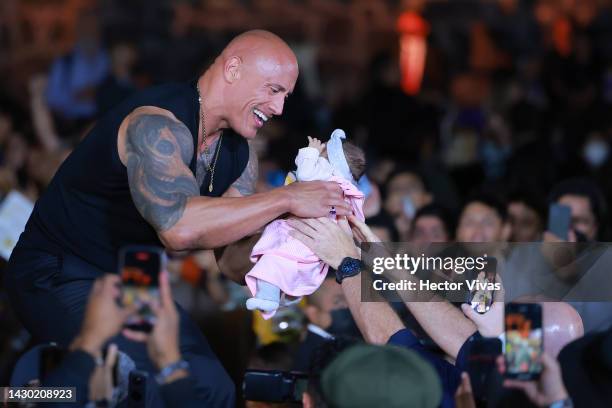 Dwayne Johnson holds a fan's baby during the black carpet for the 'Black Adam Fan Event' at Museo Anahuacalli on October 03, 2022 in Mexico City,...