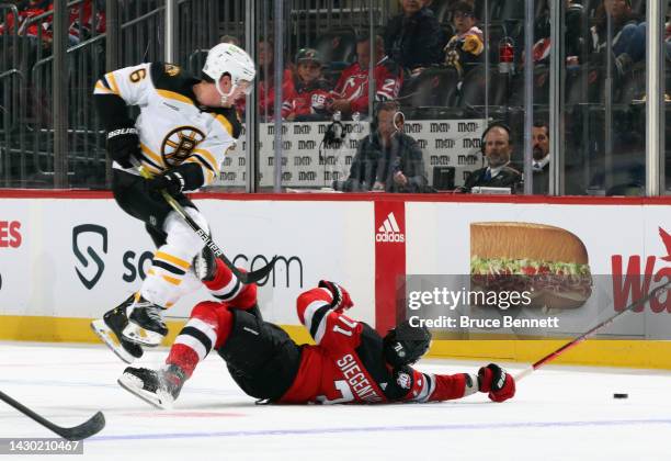 Mike Reilly of the Boston Bruins checks Jonas Siegenthaler of the New Jersey Devils during the third period at the Prudential Center on October 03,...