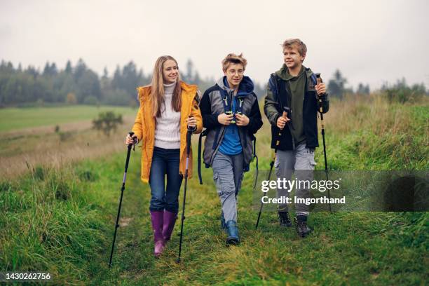 three teenagers hiking in hills on a rainy day. - october 12 stock pictures, royalty-free photos & images